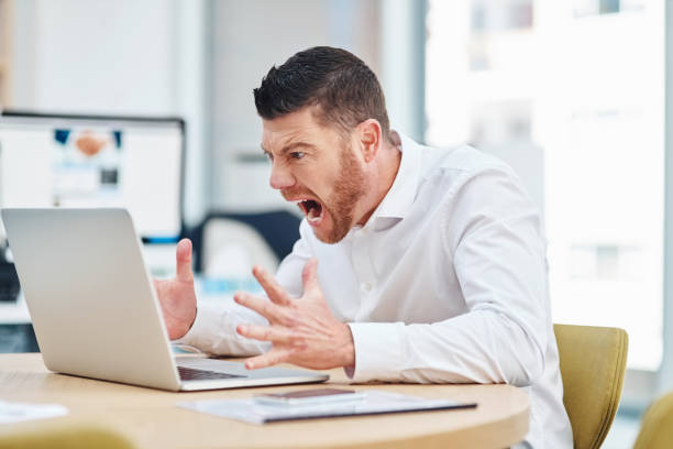 A man screams in frustration at the screen of his open laptop, demonstrating how digital transformation can quickly lead to digital anxiety if not managed properly