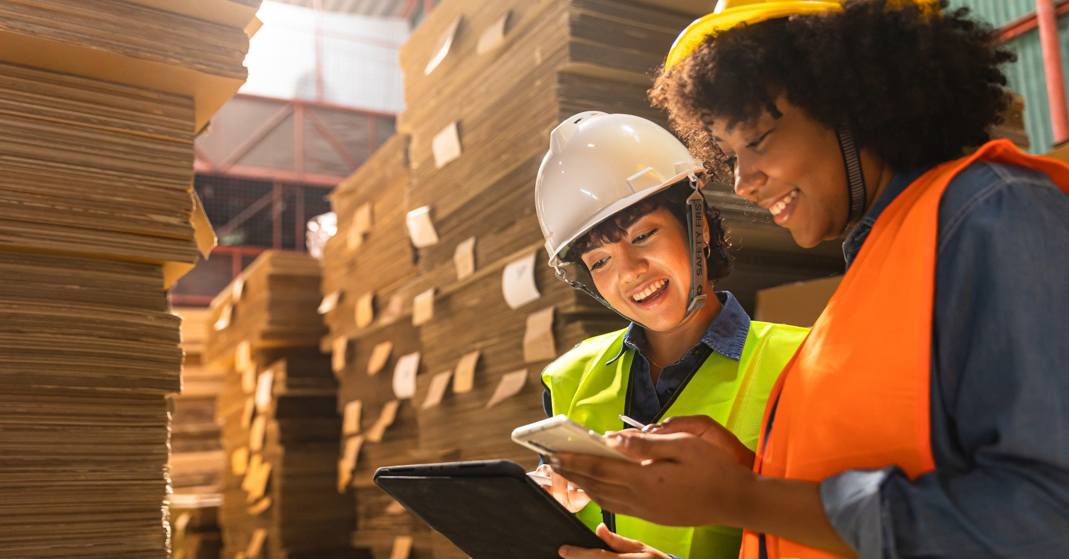 Two warehouse workers discussing over a tablet and cell phone