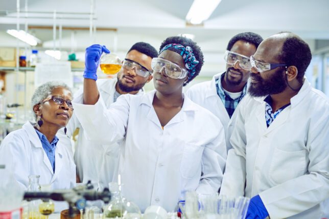 Shot of a group of lab staff in white coats working together